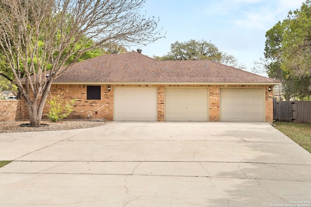 single story home featuring driveway, brick siding, fence, and roof with shingles