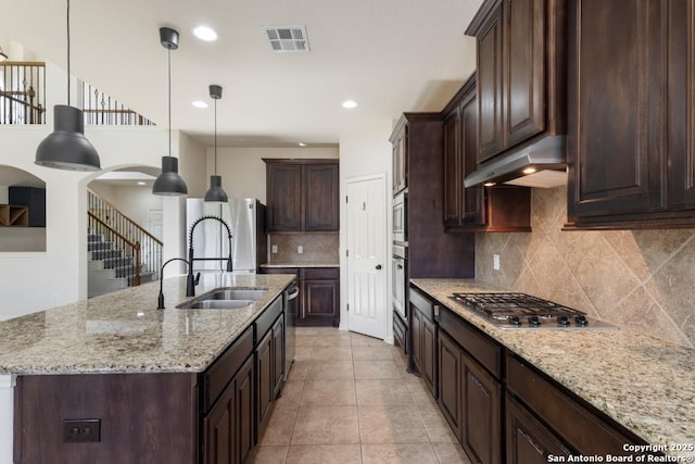 kitchen with under cabinet range hood, pendant lighting, visible vents, dark brown cabinetry, and appliances with stainless steel finishes