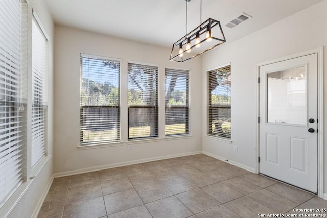 unfurnished dining area featuring plenty of natural light, baseboards, and visible vents