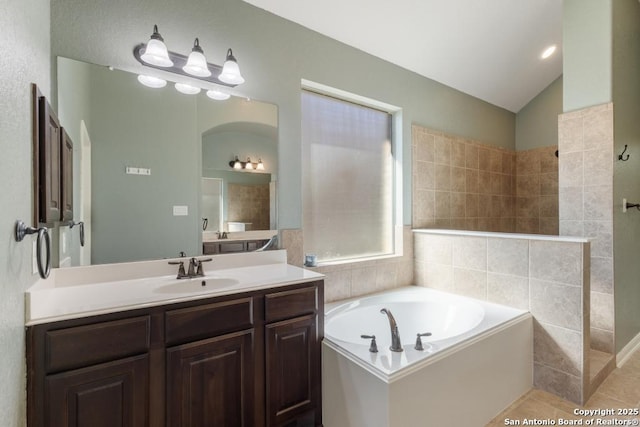 full bath featuring vaulted ceiling, a walk in shower, vanity, and a garden tub