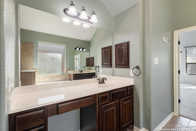 bathroom with lofted ceiling, a textured wall, tile patterned floors, and vanity