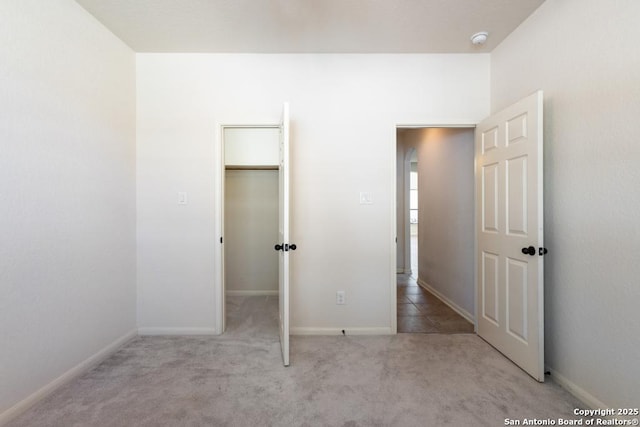 unfurnished bedroom featuring baseboards, carpet floors, and a spacious closet