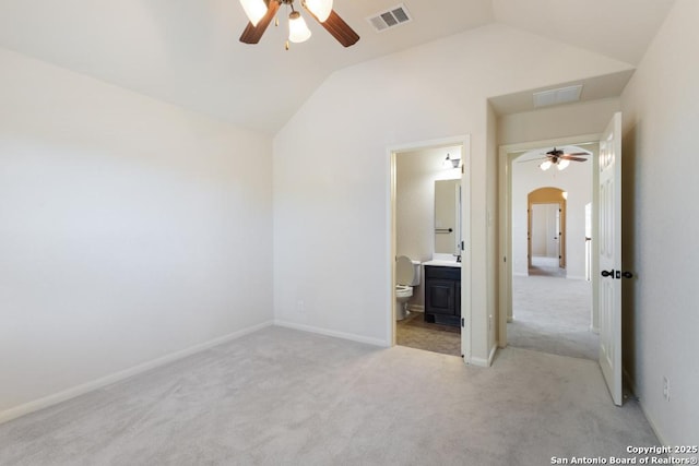 unfurnished bedroom with arched walkways, visible vents, vaulted ceiling, and light carpet