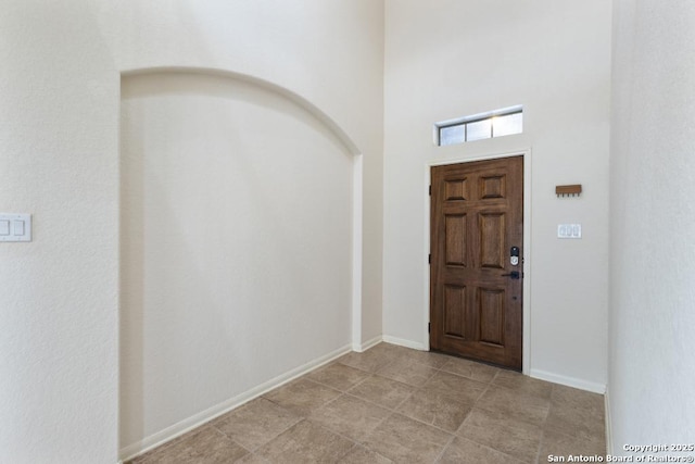 entrance foyer featuring a towering ceiling, arched walkways, and baseboards