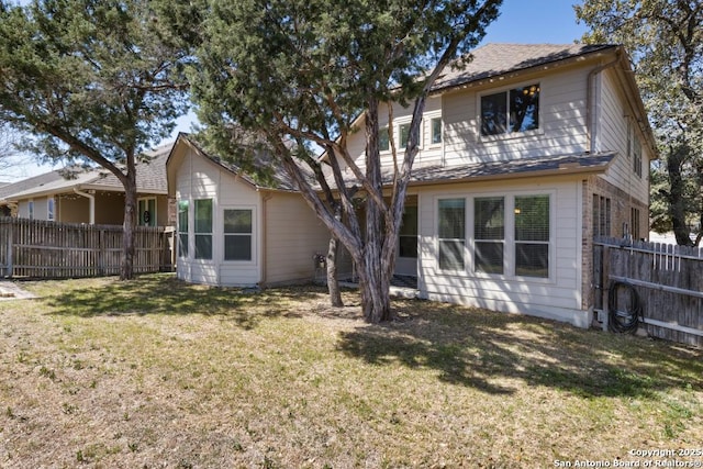 back of property with a lawn and fence