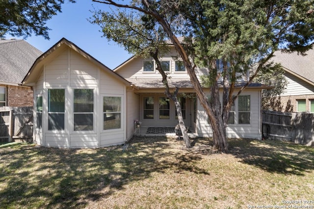 back of property with fence and a lawn