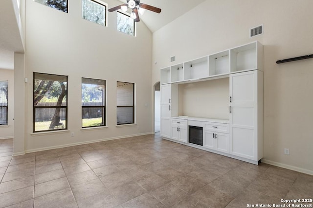 unfurnished living room with baseboards, high vaulted ceiling, ceiling fan, and visible vents