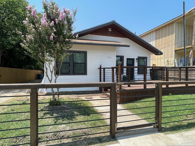 rear view of property with a lawn, fence, and a deck