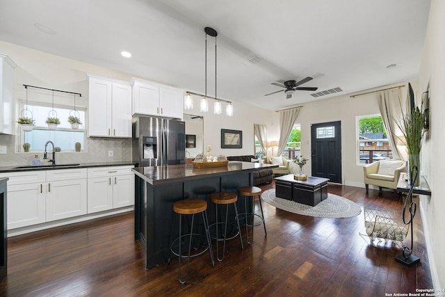 kitchen featuring stainless steel refrigerator with ice dispenser, dark countertops, dark wood-style floors, visible vents, and a ceiling fan