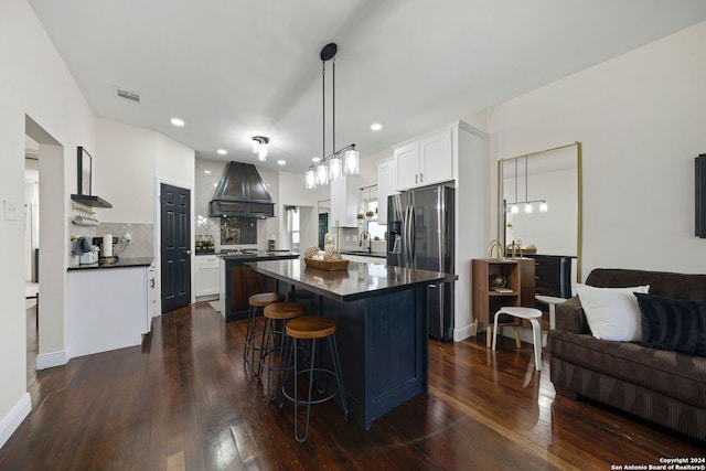kitchen with visible vents, custom exhaust hood, dark countertops, a sink, and stainless steel refrigerator with ice dispenser