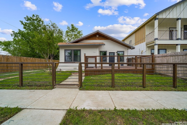 view of front of house featuring a front yard, a gate, a wooden deck, and a fenced front yard