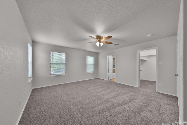 13612 Sungrove Vw, San Antonio, TX 78245 - unfurnished bedroom with a walk in closet, carpet flooring, baseboards, a textured ceiling, and visible vents