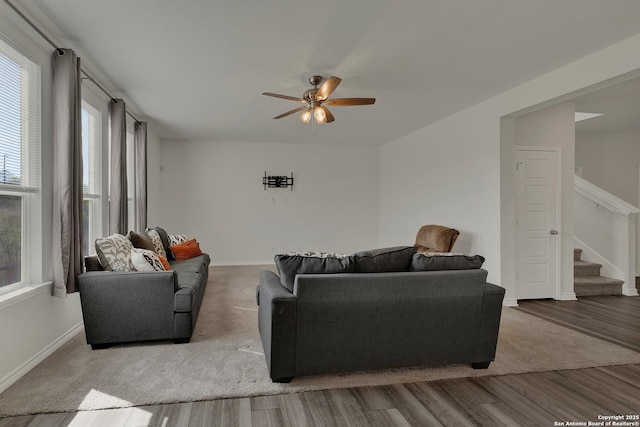 living room with baseboards, wood finished floors, stairway, and a ceiling fan