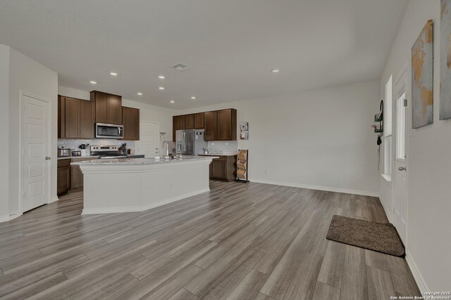 kitchen featuring light countertops, appliances with stainless steel finishes, light wood-style floors, and decorative backsplash