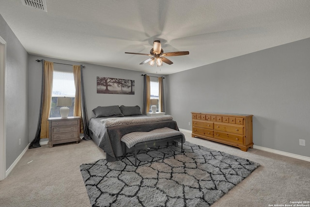 carpeted bedroom with baseboards, multiple windows, ceiling fan, and visible vents