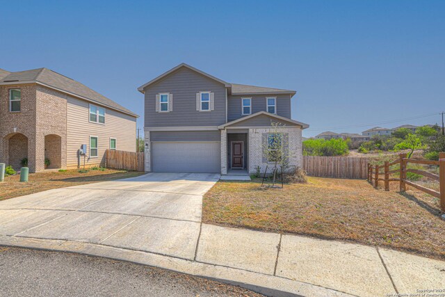 view of front of house featuring brick siding, driveway, fence, and an attached garage