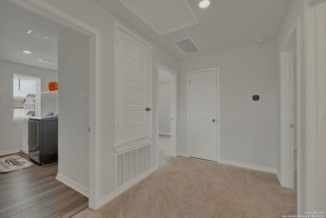 corridor with baseboards, visible vents, and washer / dryer