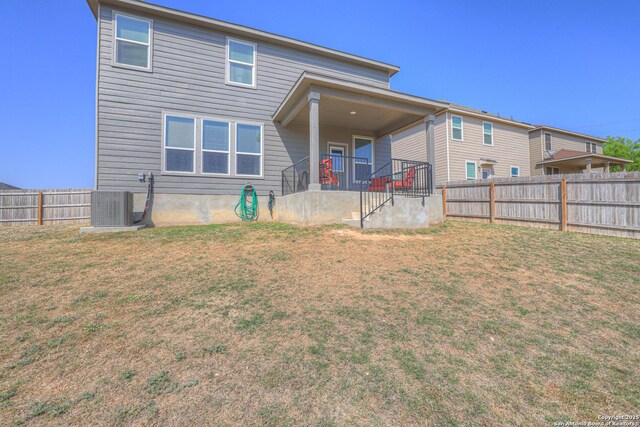 back of house with a fenced backyard, central AC unit, and a lawn