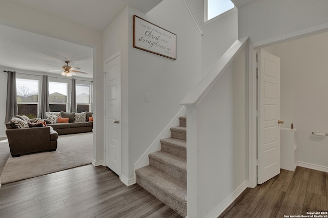 staircase with baseboards, wood finished floors, and a ceiling fan