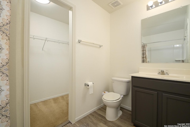 180 Elderberry, New Braunfels, TX 78130 - full bathroom with vanity, a walk in closet, toilet, visible vents, and wood finished floors