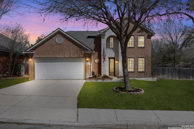 traditional home featuring fence, an attached garage, concrete driveway, brick siding, and a front lawn