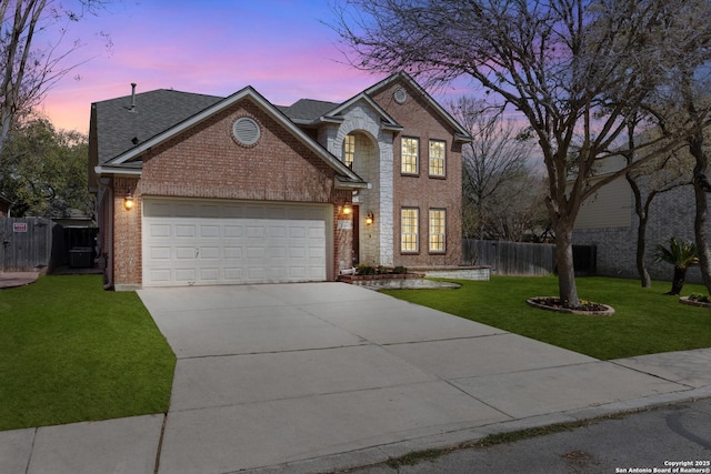 traditional-style house with driveway, fence, brick siding, a garage, and a yard