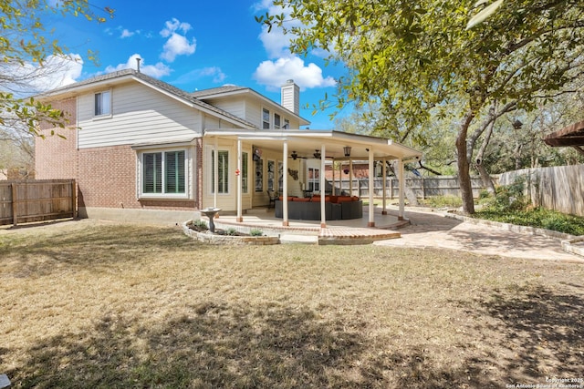 rear view of house with a patio area, brick siding, a fenced backyard, a lawn, and ceiling fan