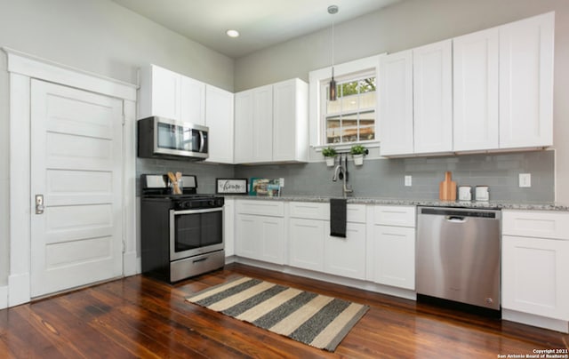 144 Ward Ave, San Antonio, TX 78223 - kitchen with white cabinetry, dark wood-style flooring, appliances with stainless steel finishes, and decorative backsplash