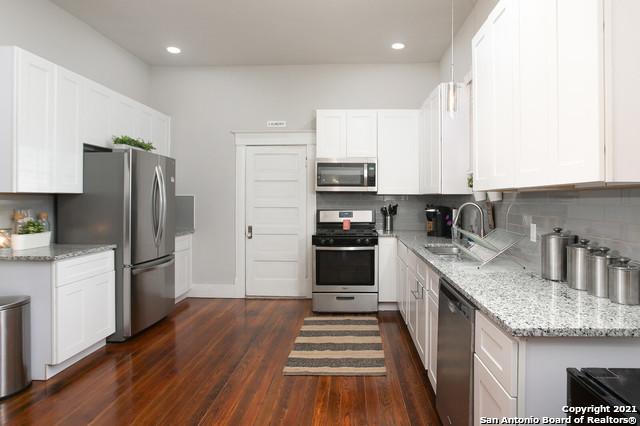 144 Ward Ave, San Antonio, TX 78223 - kitchen featuring light stone countertops, stainless steel appliances, dark wood-type flooring, a sink, and backsplash