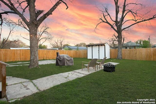 144 Ward Ave, San Antonio, TX 78223 - yard at dusk with a patio, a fenced backyard, an outbuilding, a fire pit, and a shed