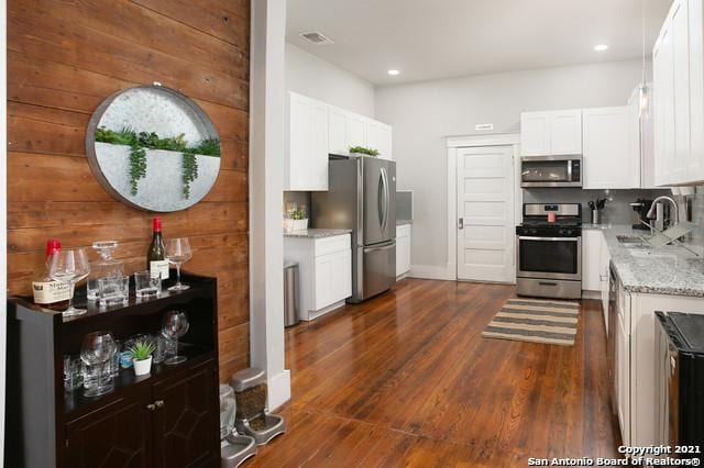144 Ward Ave, San Antonio, TX 78223 - kitchen featuring light stone counters, a sink, white cabinetry, stainless steel appliances, and dark wood-type flooring