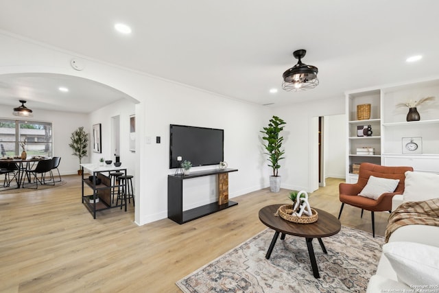 living room with baseboards, light wood-type flooring, arched walkways, and recessed lighting