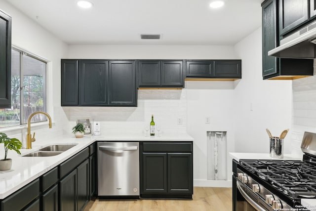 kitchen featuring stainless steel appliances, under cabinet range hood, a sink, visible vents, and light wood-style flooring