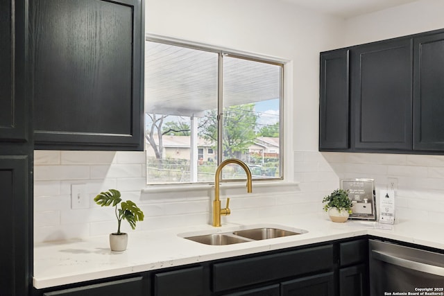 kitchen with tasteful backsplash, dark cabinetry, a sink, and dishwasher