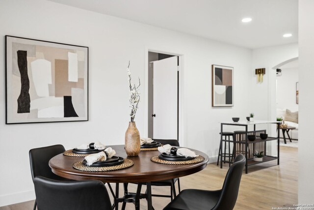 dining area featuring recessed lighting, arched walkways, baseboards, and wood finished floors