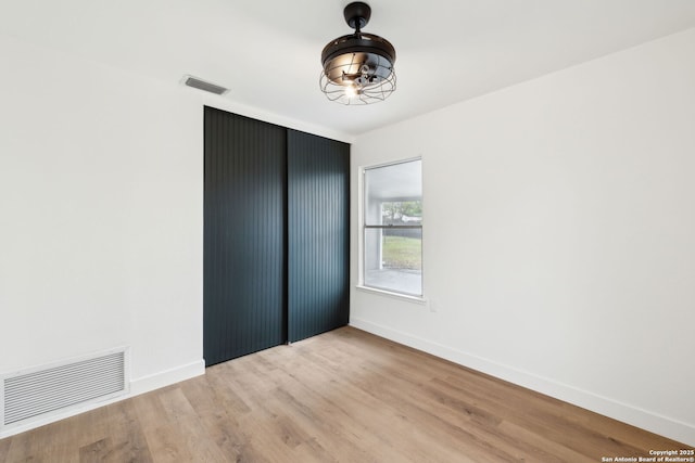 unfurnished bedroom with baseboards, visible vents, and wood finished floors