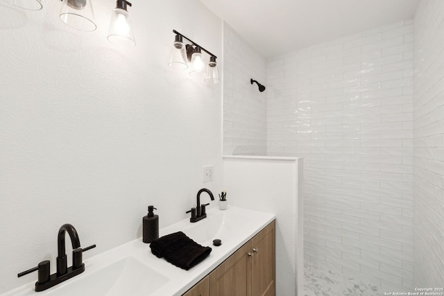 full bath with double vanity, a sink, and tiled shower