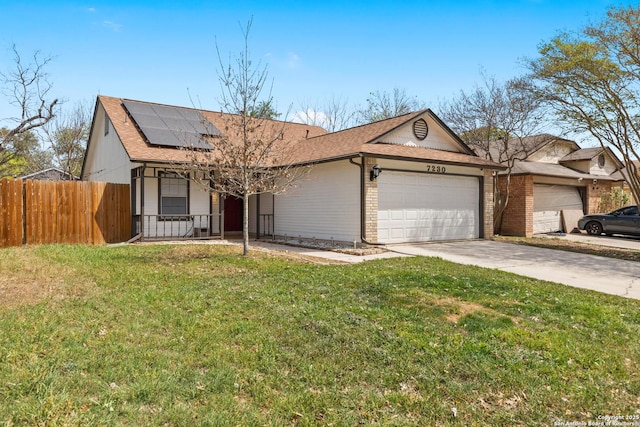ranch-style house featuring a front yard, driveway, solar panels, and fence