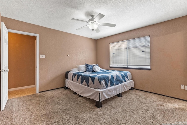 bedroom featuring carpet flooring, a ceiling fan, a textured wall, and a textured ceiling