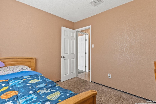 bedroom with visible vents, a textured wall, and carpet flooring