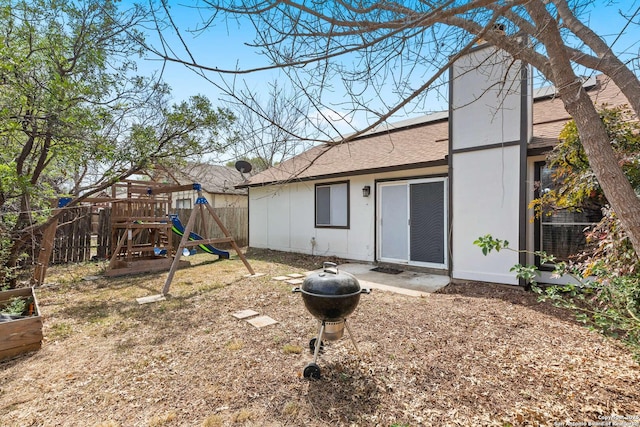 back of property with a playground, central AC unit, a shingled roof, and fence