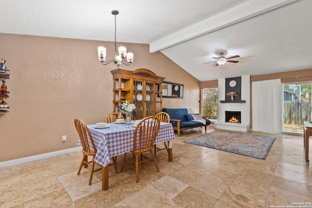 dining room with a textured wall, lofted ceiling with beams, ceiling fan with notable chandelier, baseboards, and a fireplace