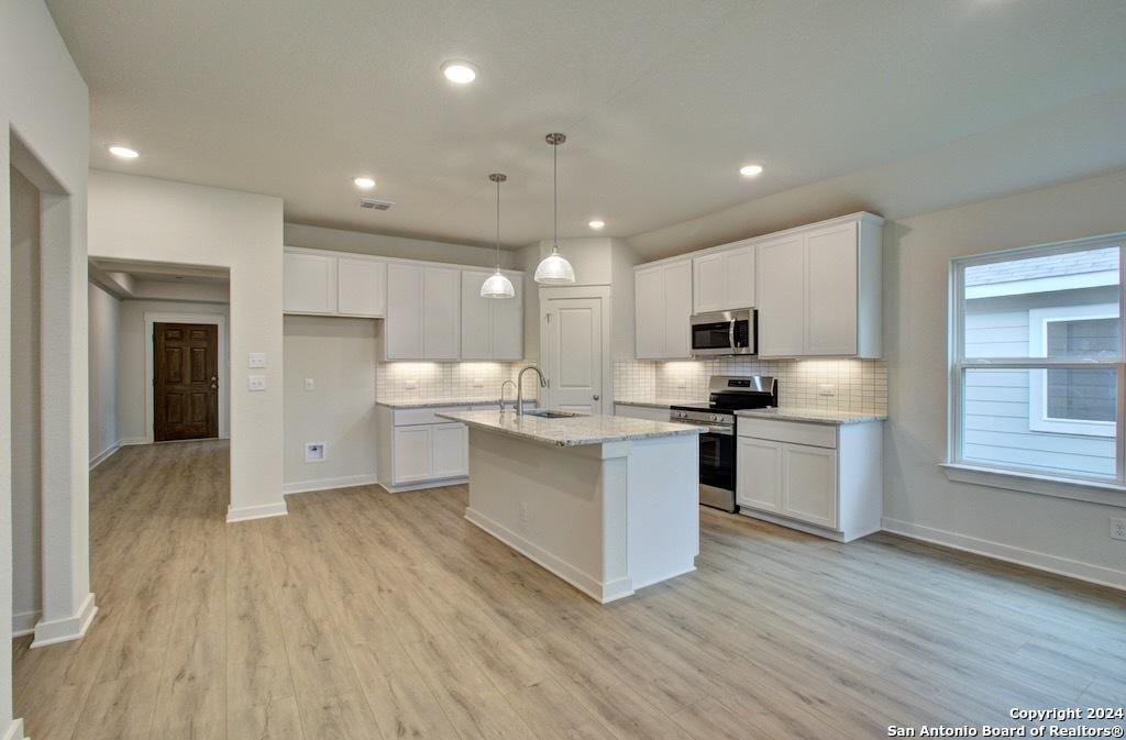 kitchen featuring white cabinetry, backsplash, a sink, and stainless steel appliances