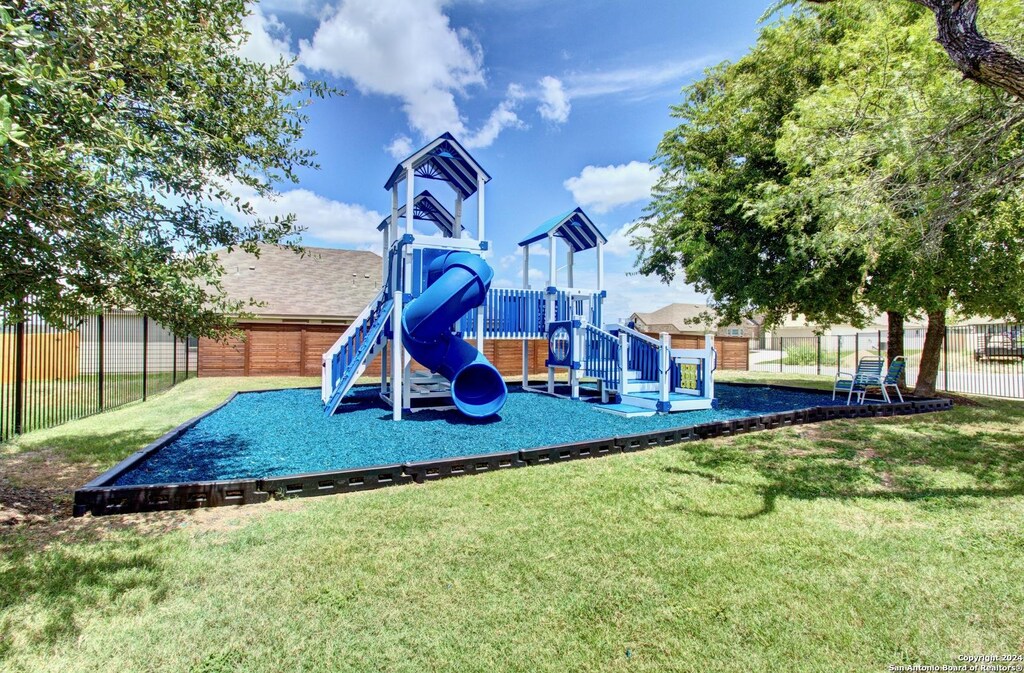 community jungle gym with fence and a yard