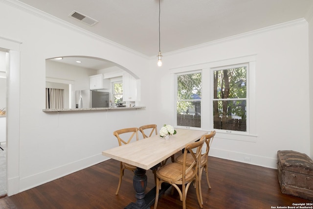 dining space with crown molding, wood finished floors, baseboards, visible vents, and arched walkways