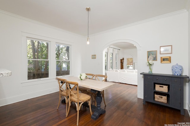 dining room with dark wood-style floors, crown molding, arched walkways, and baseboards