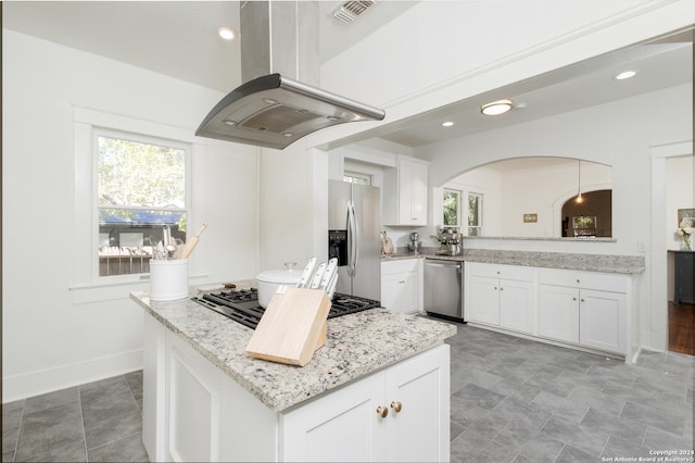 kitchen with white cabinets, visible vents, stainless steel appliances, arched walkways, and island range hood