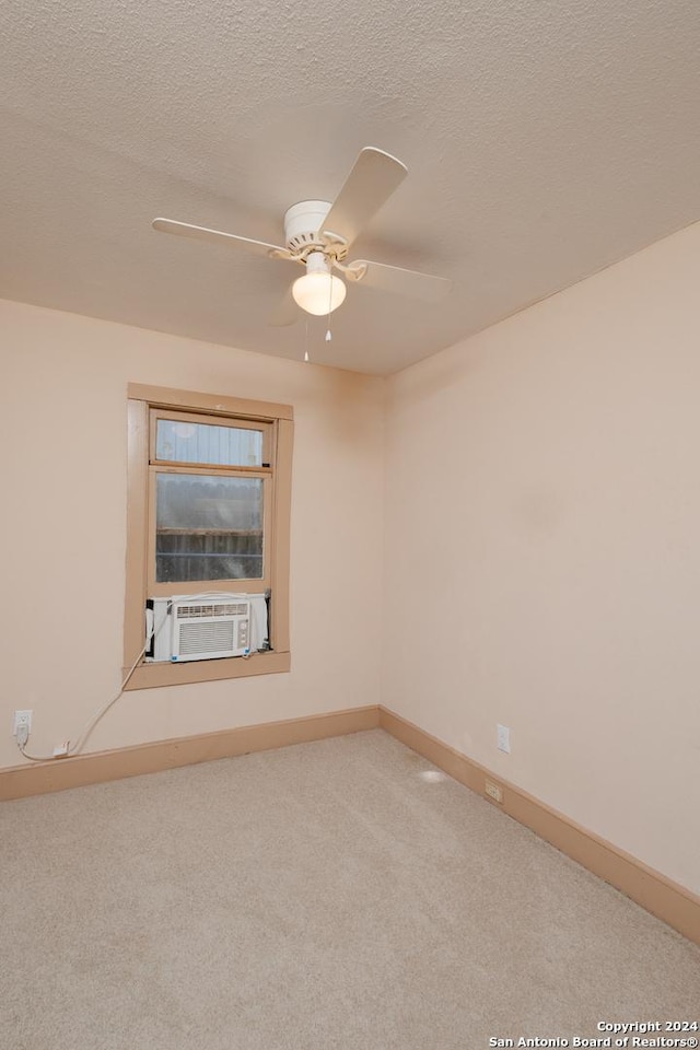 empty room featuring cooling unit, carpet, baseboards, a textured ceiling, and a ceiling fan