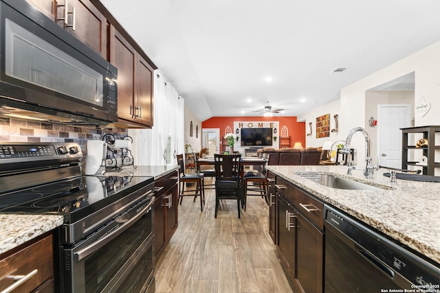 kitchen featuring tasteful backsplash, light wood-type flooring, a sink, a ceiling fan, and black appliances
