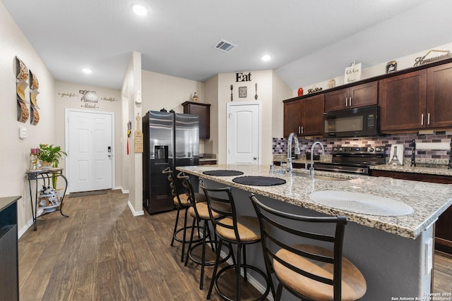kitchen featuring dark wood-type flooring, visible vents, stainless steel appliances, and dark brown cabinets